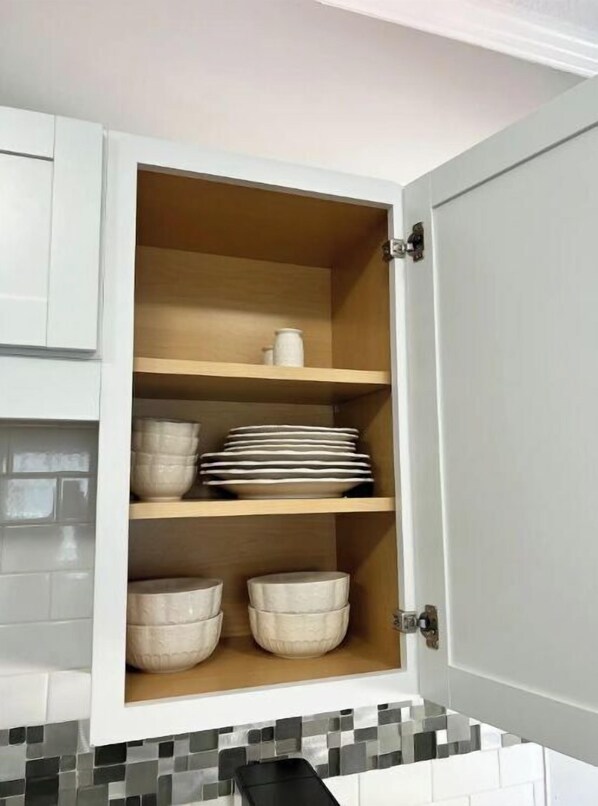 A kitchen cabinet with three shelves, each holding bowls and plates. - Private Pool and Patio (Orange Park)