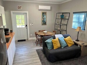 A compact living space with a kitchenette, dining area, and a sofa with cushions. - Private Pool and Patio (Orange Park)