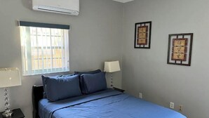Ein Schlafzimmer mit einem Bett, zwei Nachttischen, einem Fenster und Wanddekorationen.
