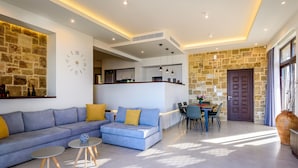 A modern living room with a sofa, coffee table, and dining area. - Sunset Villa - Panorama Sea View Villa (Platanias)