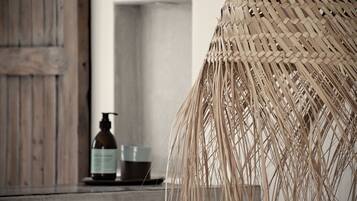 A room with a rustic wooden door, a woven basket, and a bottle of liquid soap on a table.