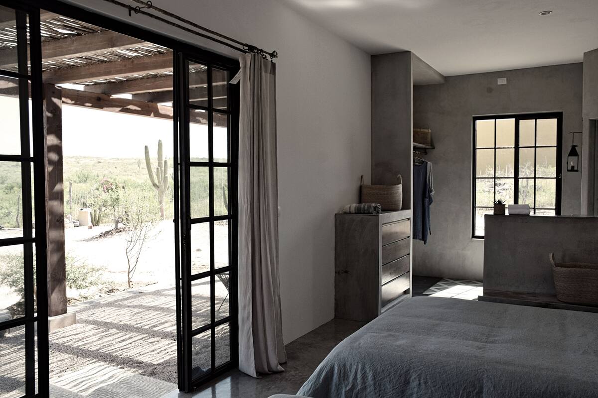 Un dormitorio con una cama grande, un aparador y una ventana con vistas a un paisaje desértico.