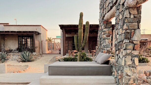 A pool with a stone wall and a cactus in the foreground. - Desierto Azul (Todos Santos)