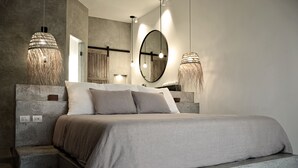 Une chambre moderne avec un grand lit, un miroir et deux luminaires suspendus.