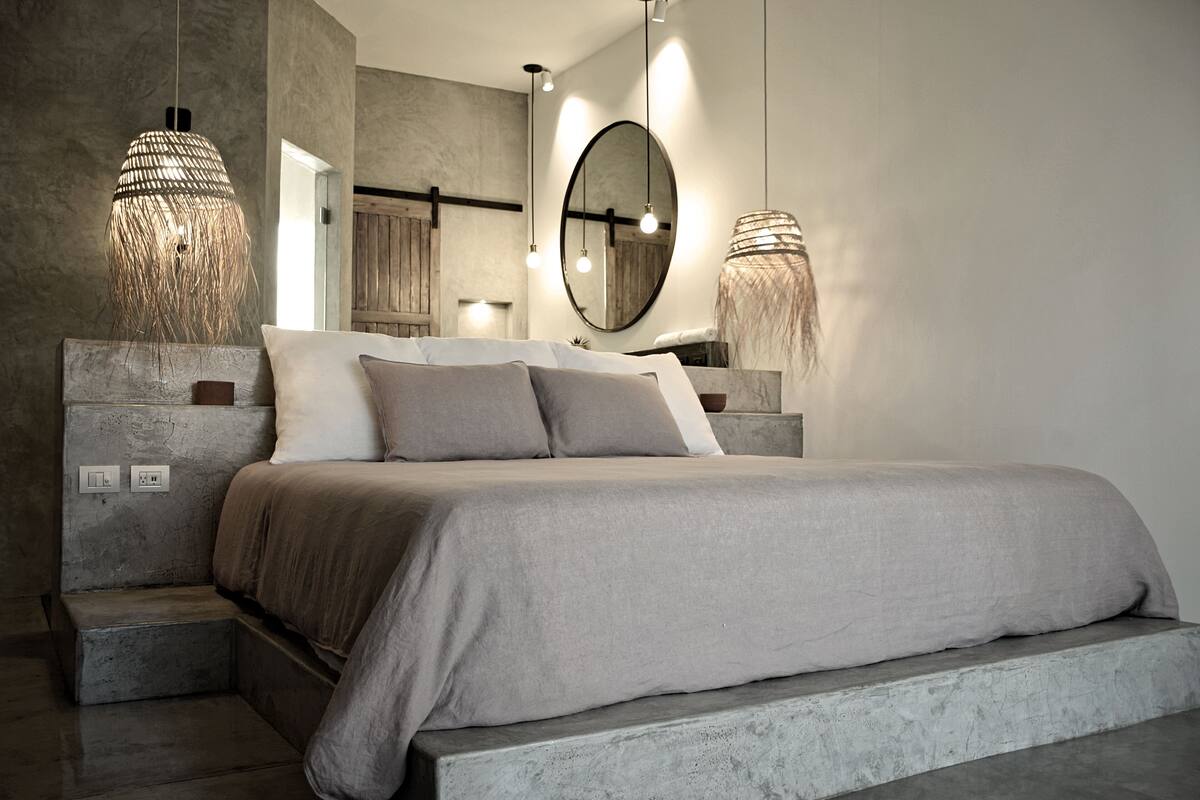 Un dormitorio moderno con una cama grande, un espejo y dos lámparas colgantes.