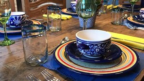 A dining table set with blue and white patterned plates, a vase with pink flowers, and clear glasses.
