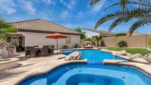 Un patio trasero con piscina, muebles de jardín y zona de barbacoa.