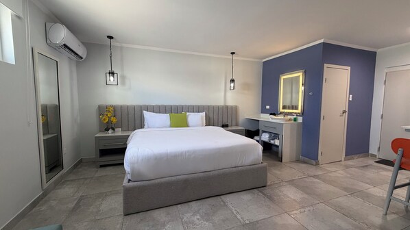 Habitación de hotel con cama, mesita de noche, cómoda y espejo.