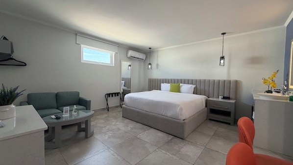 Une chambre d’hôtel moderne dotée d’un grand lit, d’un coin salon avec une table, d’un bureau et d’une salle de bain avec un lavabo et un miroir.