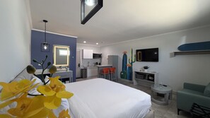 Habitación de hotel con cama, escritorio, silla, televisor y una mesita.