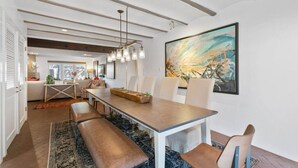 Un comedor moderno con una mesa larga, bancos y un cuadro abstracto grande en la pared.