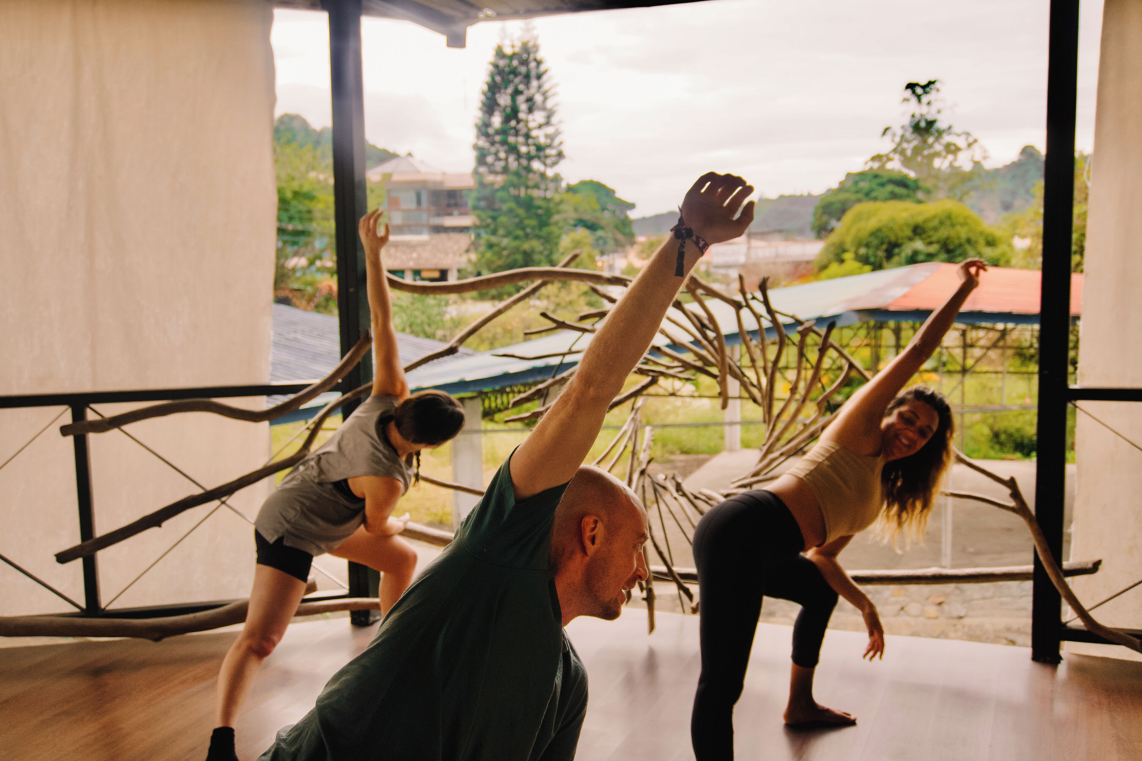 A group of people practicing yoga in a room with a large window overlooking a garden.