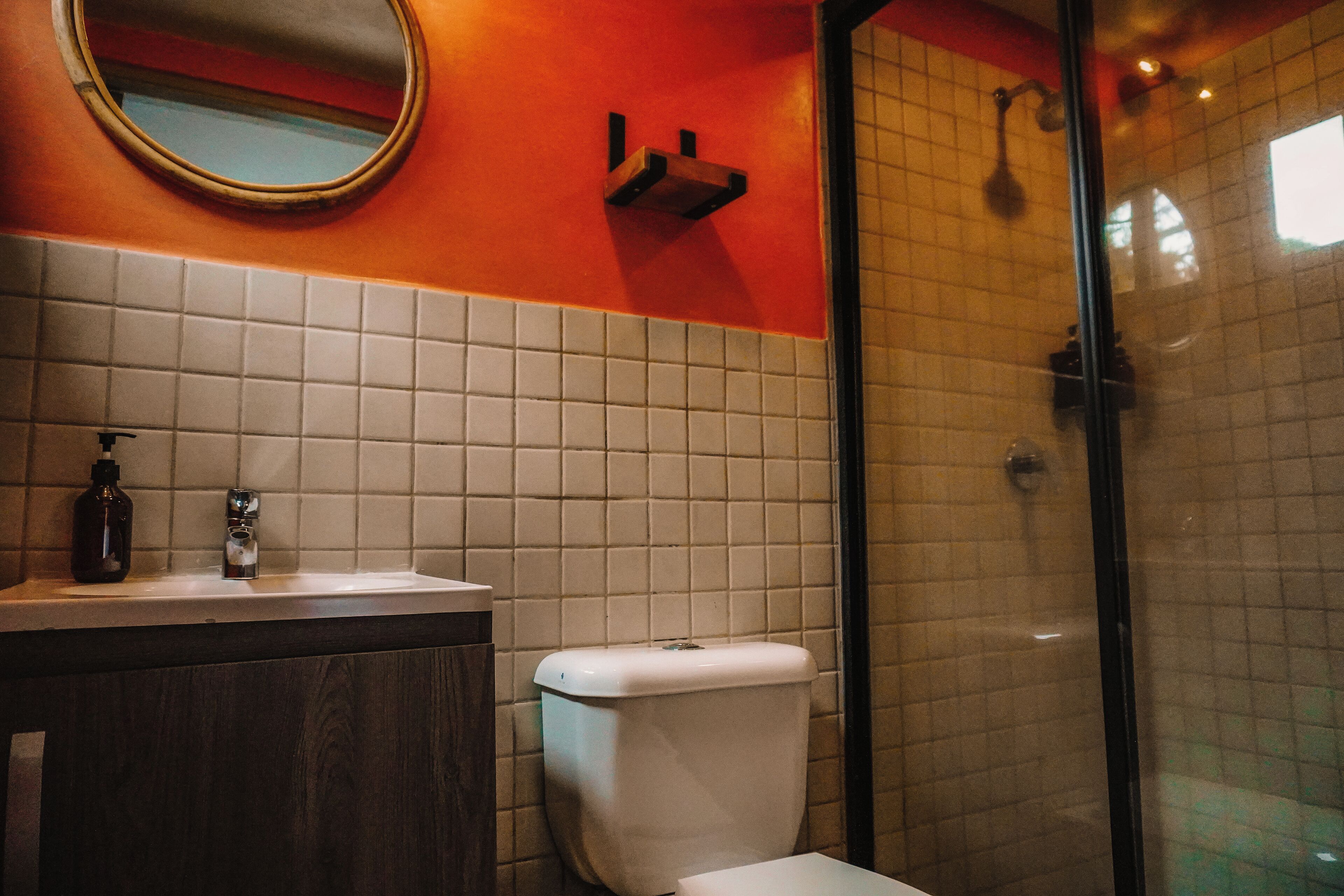 Ein Badezimmer mit einer weißen Toilette, einem Waschbecken mit Seifenspender und einem Spiegel an der Wand.