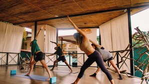 A yoga class in a room with wooden floors and a high ceiling.