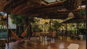 An outdoor wooden deck with wicker furniture, a hammock, and hanging planters.