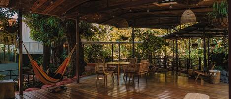 An outdoor wooden deck with wicker furniture, a hammock, and hanging planters.