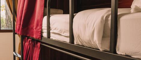 Dormitorio con literas, cortina roja, paredes de madera y ventana con cortinas.