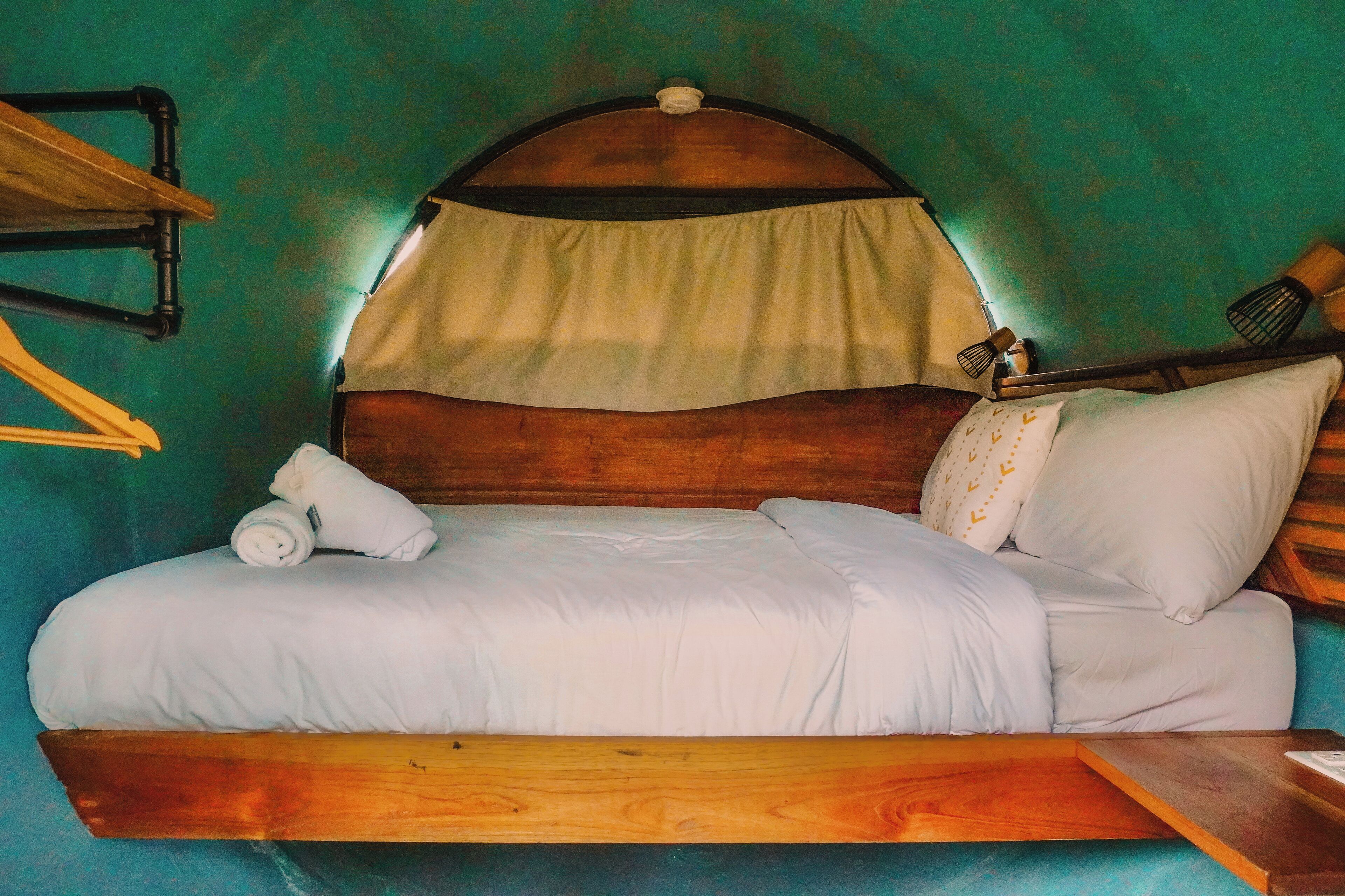 Una cama con estructura de madera, ropa de cama blanca y dosel.