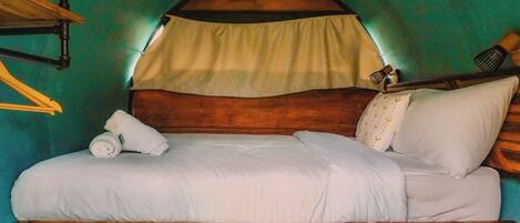 Una cama con estructura de madera, ropa de cama blanca y dosel.