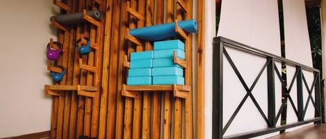 Un gimnasio con paredes de madera, colchonetas de yoga azules, pesas de kettlebell y mancuernas.
