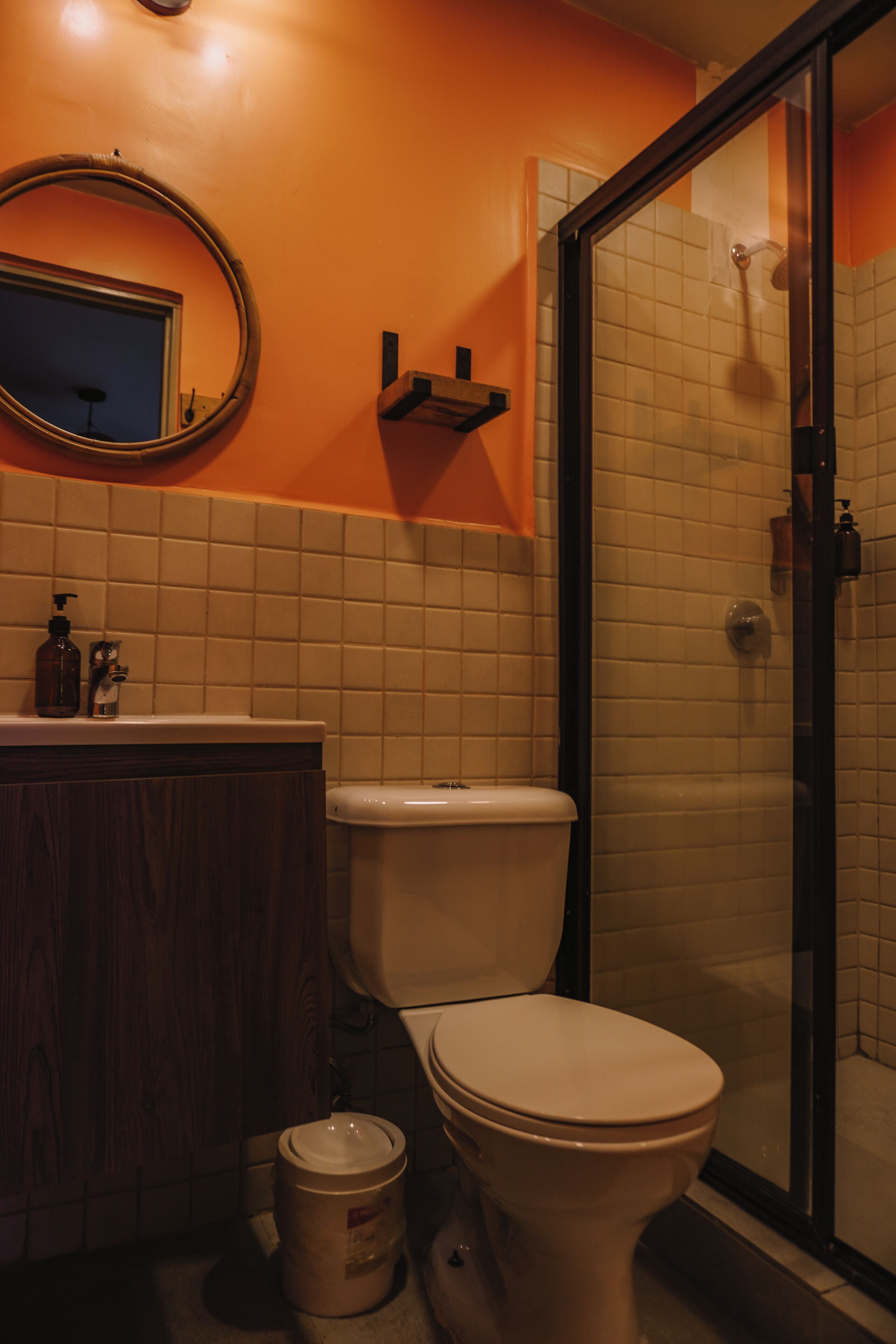 A bathroom with a toilet, a sink with a mirror, and a shower area.