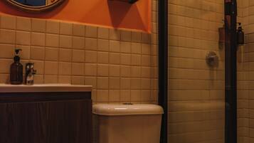 Een badkamer met toilet, wastafel met spiegel en douche.