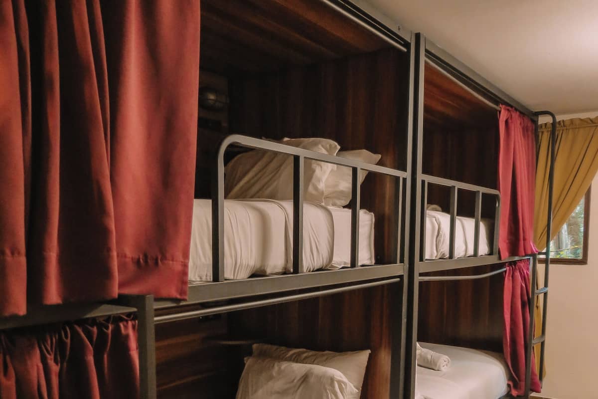 A bunk bed room with wooden flooring and curtains.