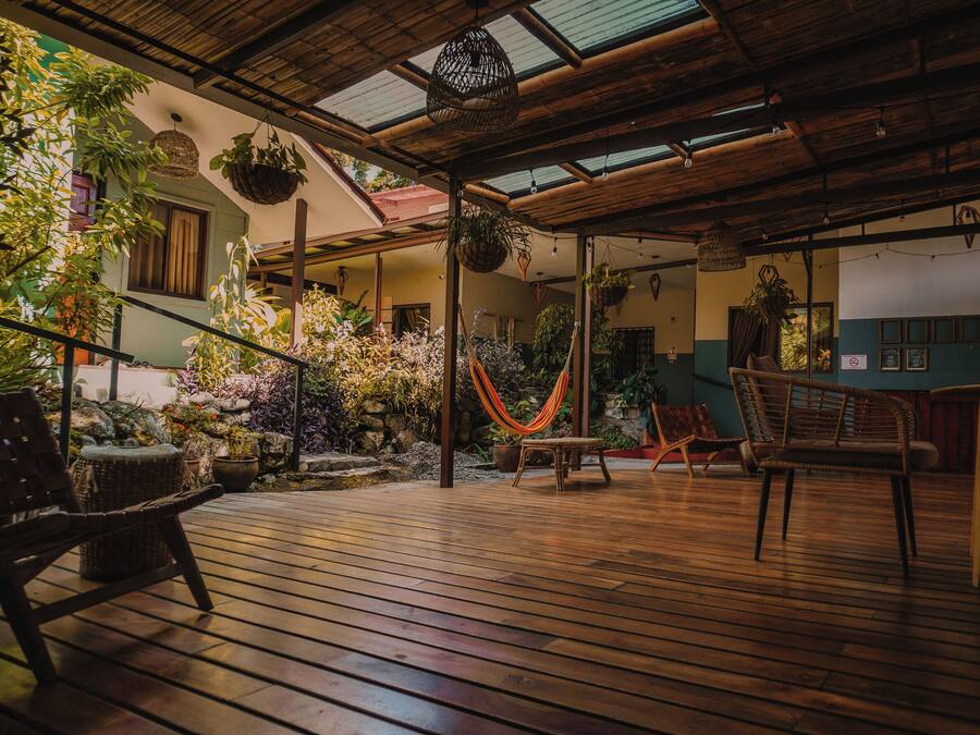 A wooden deck with wicker furniture, hanging plants, and a hammock.