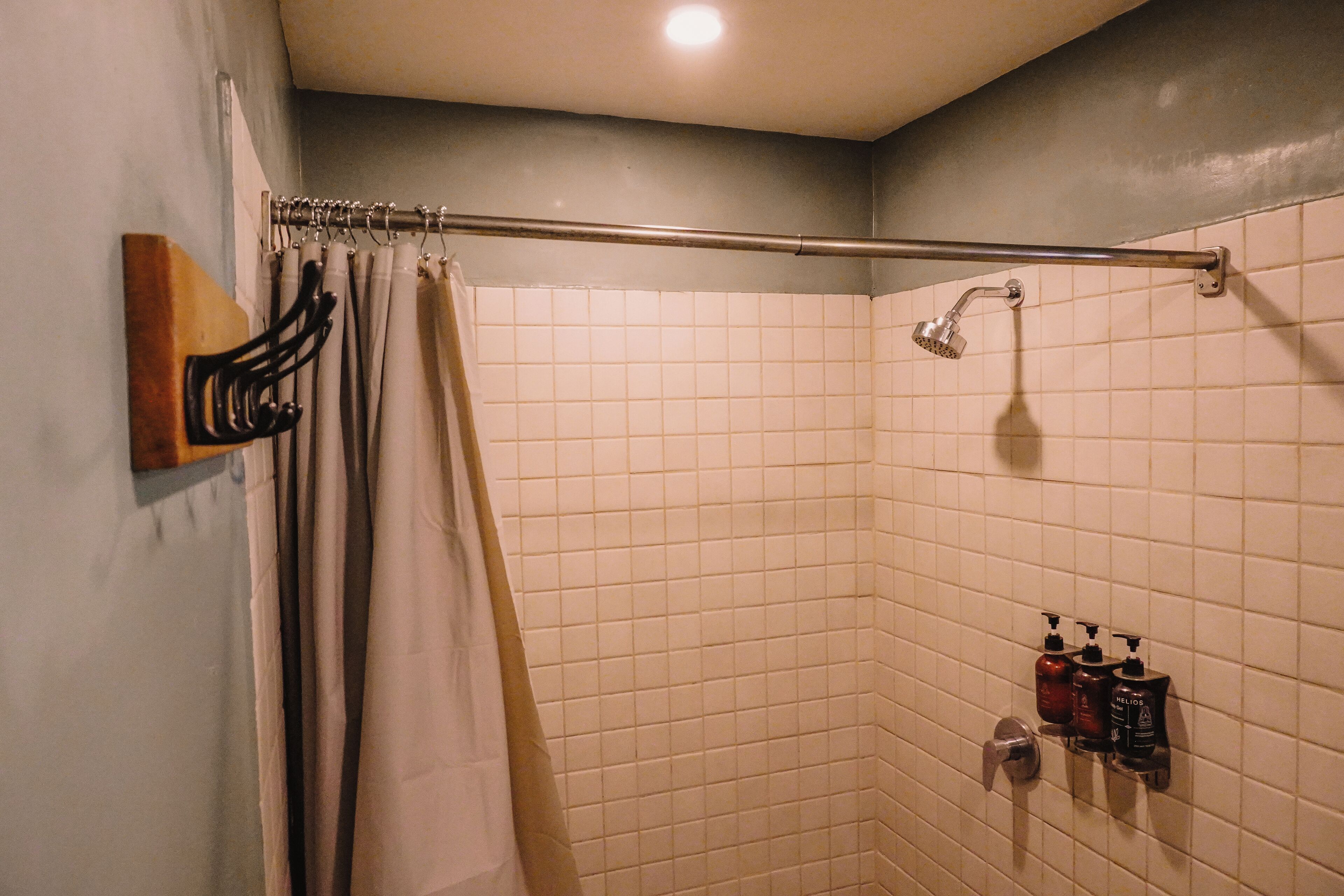 Un bagno con doccia, un porta asciugamani e due erogatori di sapone a parete.