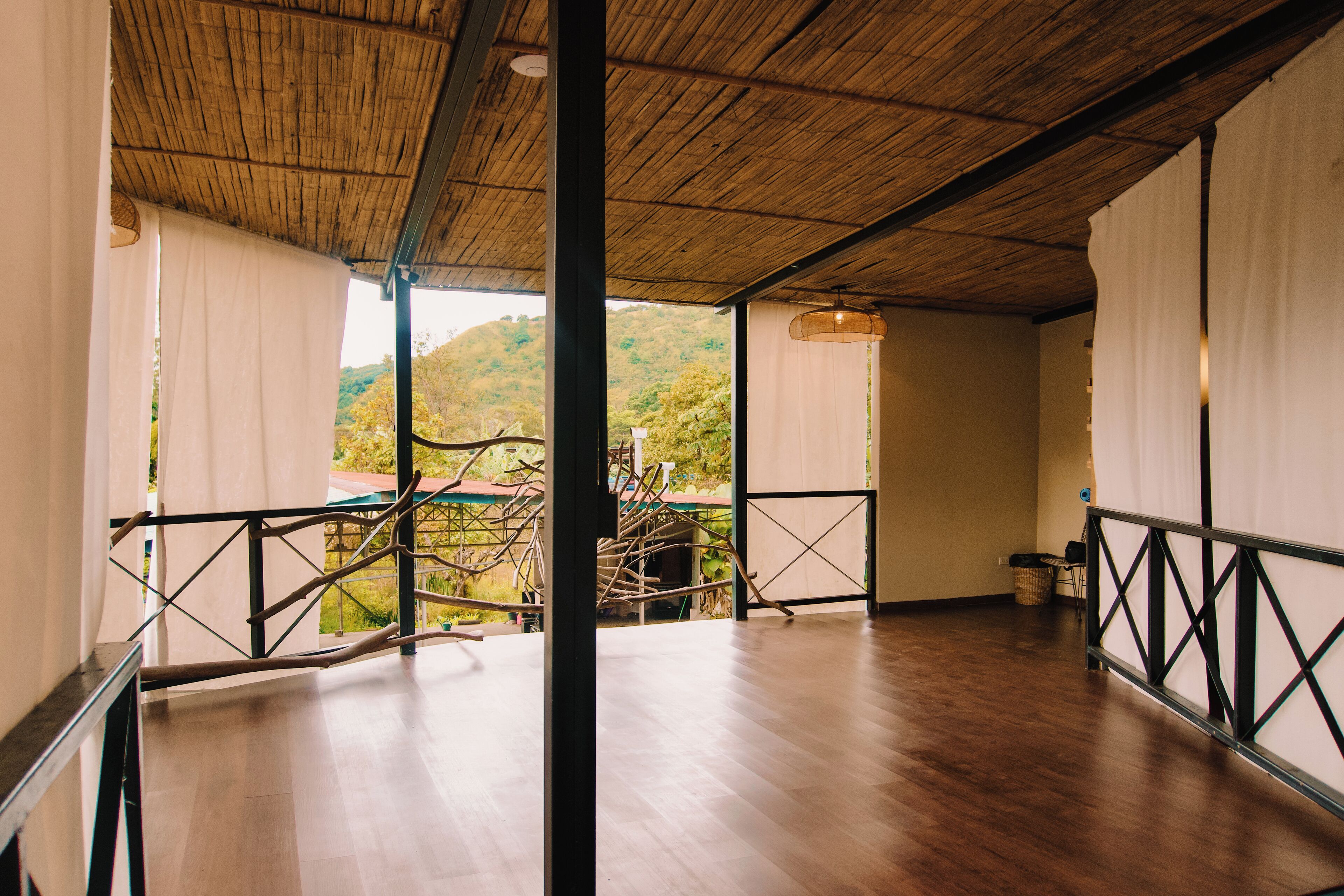 Une pièce spacieuse avec un plancher en bois, un toit de chaume et une vue sur un paysage montagneux.