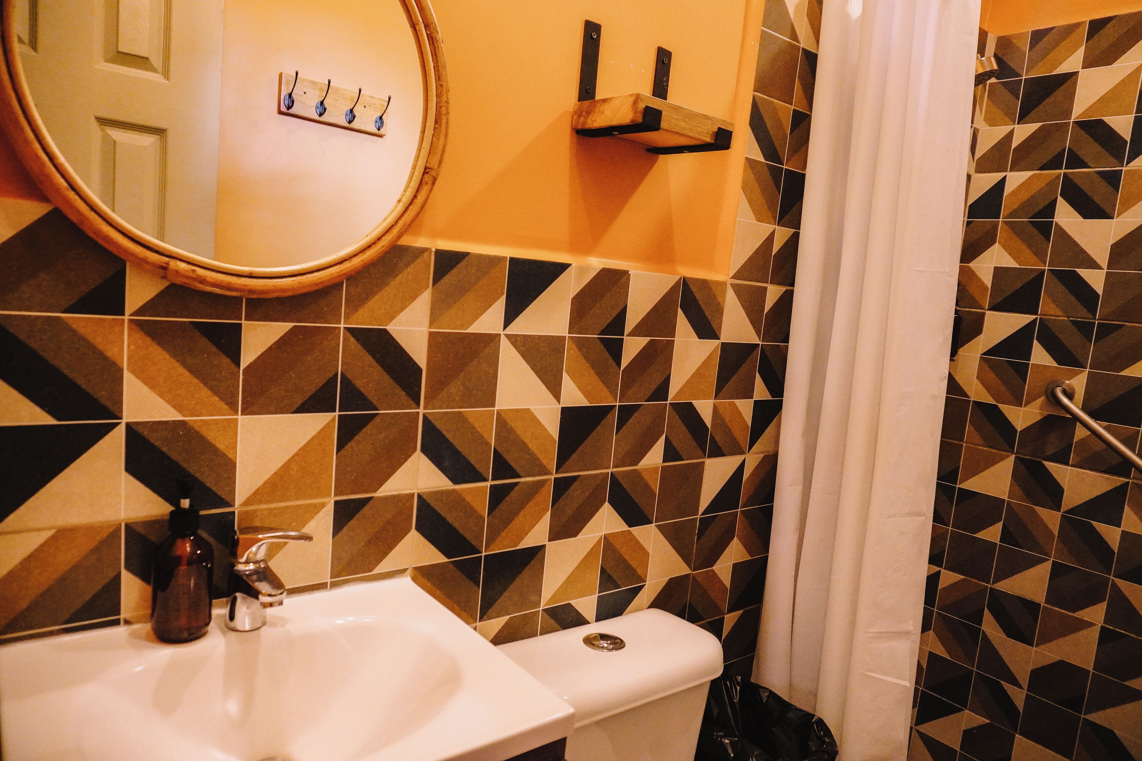 A bathroom with a sink, mirror, and patterned tiles.