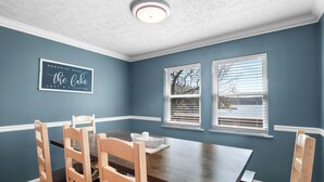 Un comedor con una mesa y sillas de madera, una pared azul de acento y una lámpara en el techo.