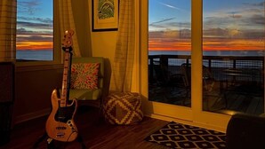 A room with a large window overlooking a sunset, a guitar, a patterned ottoman, and a framed artwork on the wall. - BEACHFRONT
Gorgeous View!!!
OCEANFRONT
Sunday to Sunday (Eastpoint)
