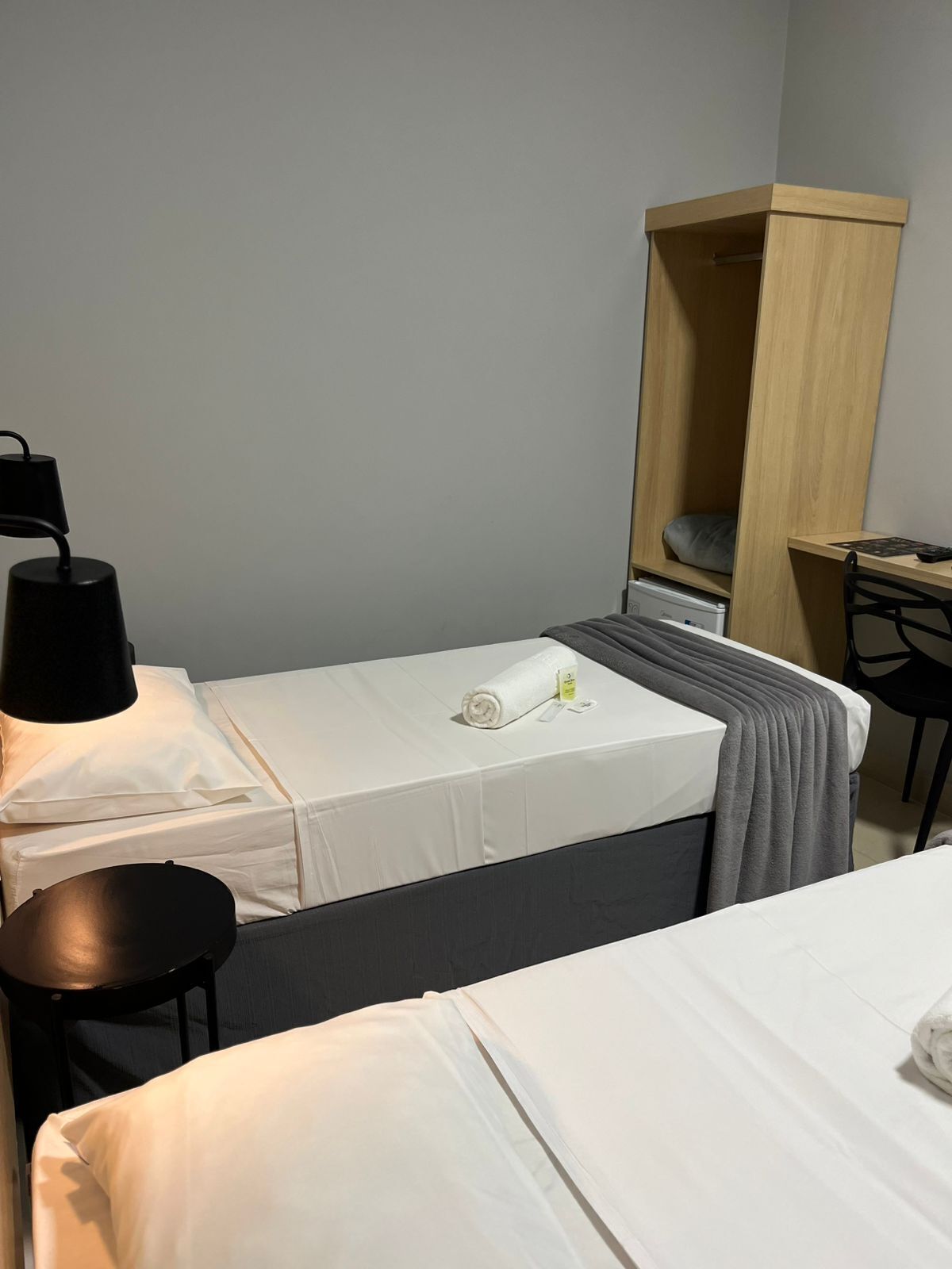 Habitación de hotel con dos camas, un escritorio, una silla y un armario.