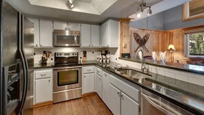 A modern kitchen with stainless steel appliances, a wooden accent wall, and a large window. - Ski In Ski Out Stagecoach Lift at Heavenly 3BR 3BA (Stateline)