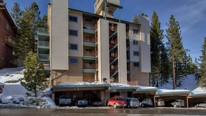 A multi-story hotel with a central staircase, parking garage, and a ski slope in the background. - Ski In Ski Out Stagecoach Lift at Heavenly 3BR 3BA (Stateline)