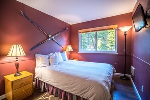 A bedroom with a bed, two bedside lamps, a nightstand, a window, and a TV mounted on the wall. - Ski In Ski Out Stagecoach Lift at Heavenly 3BR 3BA (Stateline)