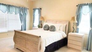 Une chambre à coucher avec un lit en bois, deux tables de chevet et des rideaux bleu clair.