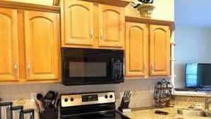 Une cuisine avec des meubles de rangement en bois, un four à micro-ondes, une cuisinière et un lave-vaisselle.