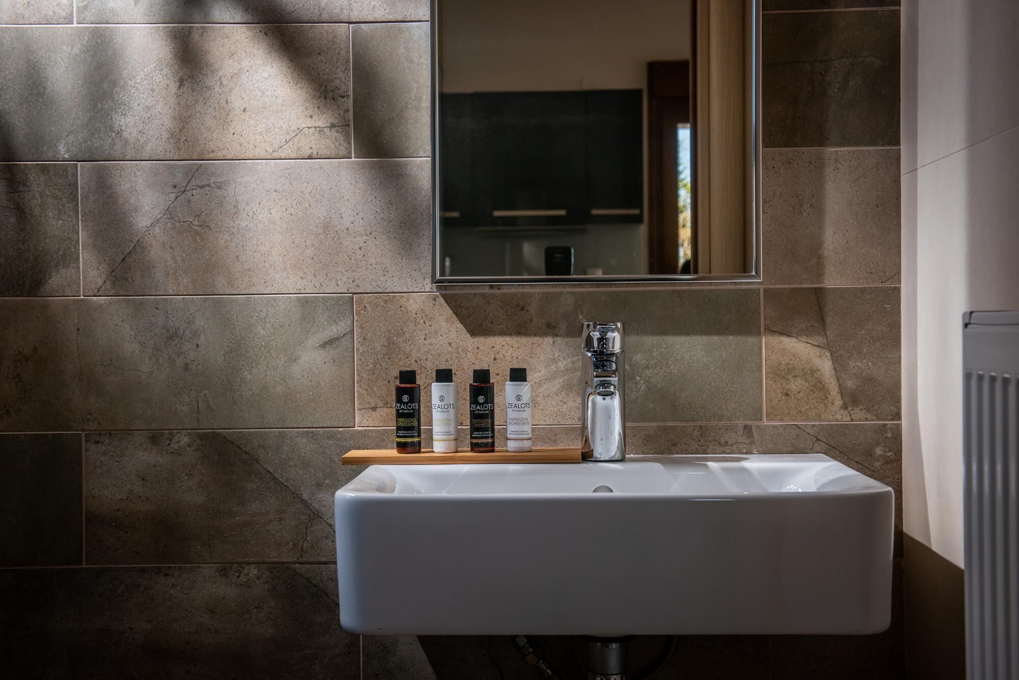 A bathroom with a white sink, a mirror, and a shelf with toiletries.