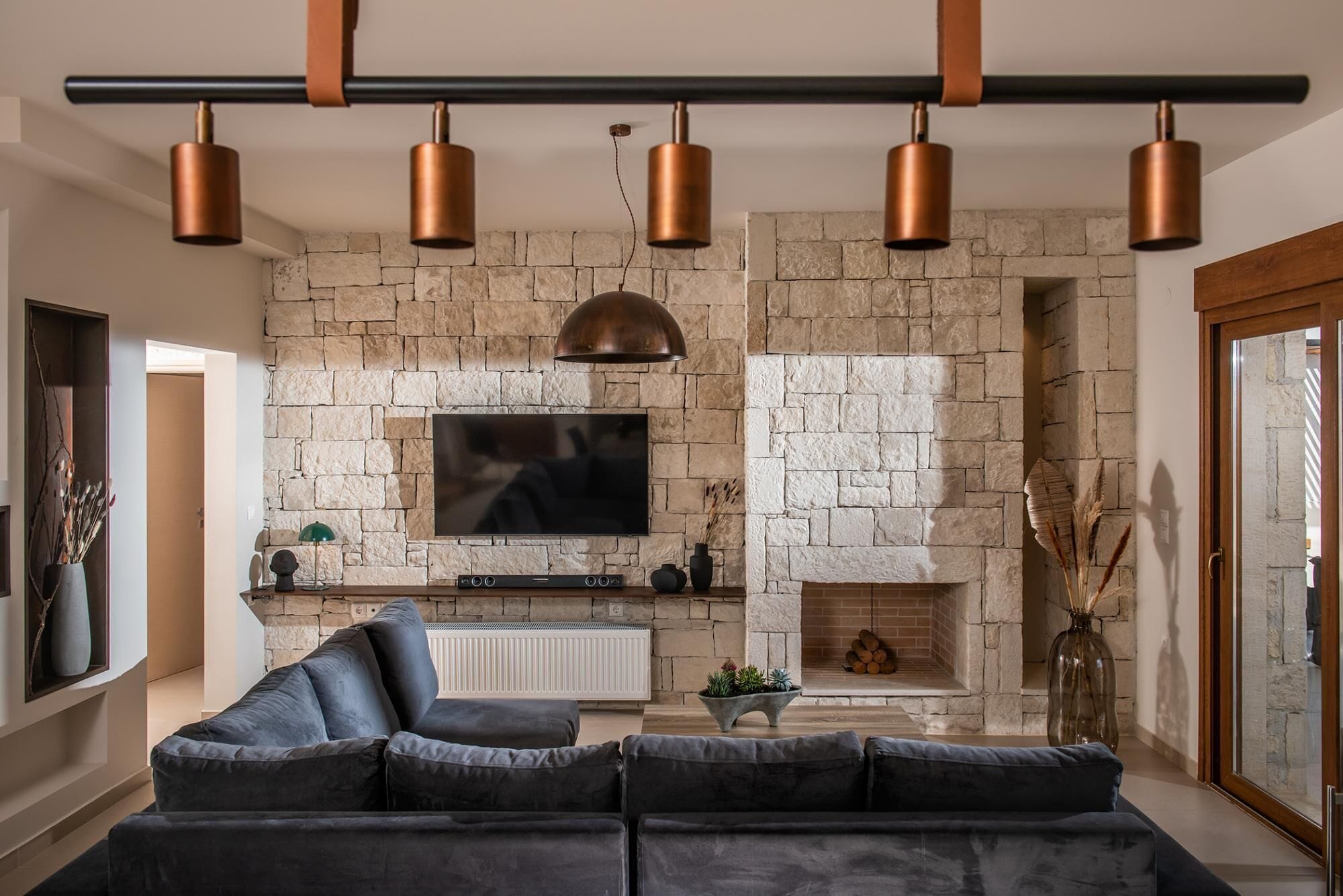 Una sala de estar moderna con chimenea de piedra, un televisor de pantalla plana grande y un sofá modular.