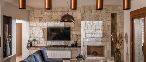 Una sala de estar moderna con chimenea de piedra, un televisor de pantalla plana grande y un sofá modular.