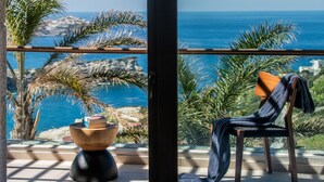 A balcony with a view of the sea, a wooden chair, and a small table with a book. - Alpha House in Crete (Malevizi)