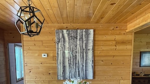 En matplats med ett träbord, sex stolar, en vas med blommor och en tavla som hänger på väggen.