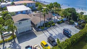 An aerial view of a coastal hotel with a parking lot, beach access, and a view of the ocean. - Beautiful Beachfront Home with Private Pool/ Firepit /on the Gulf (Indian Rocks Beach)