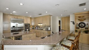 A modern kitchen with granite countertops, stainless steel appliances, and wooden cabinetry. - Beautiful Beachfront Home with Private Pool/ Firepit /on the Gulf (Indian Rocks Beach)