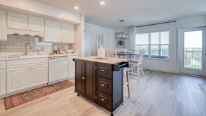 Una cocina moderna con armarios blancos, una isla negra y un comedor con vistas.