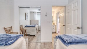 Un dormitorio con dos camas, una silla de madera, una mesita de noche y un espejo.