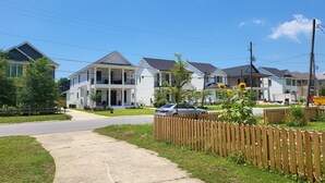Rua residencial com casas, calçada e cerca de madeira.