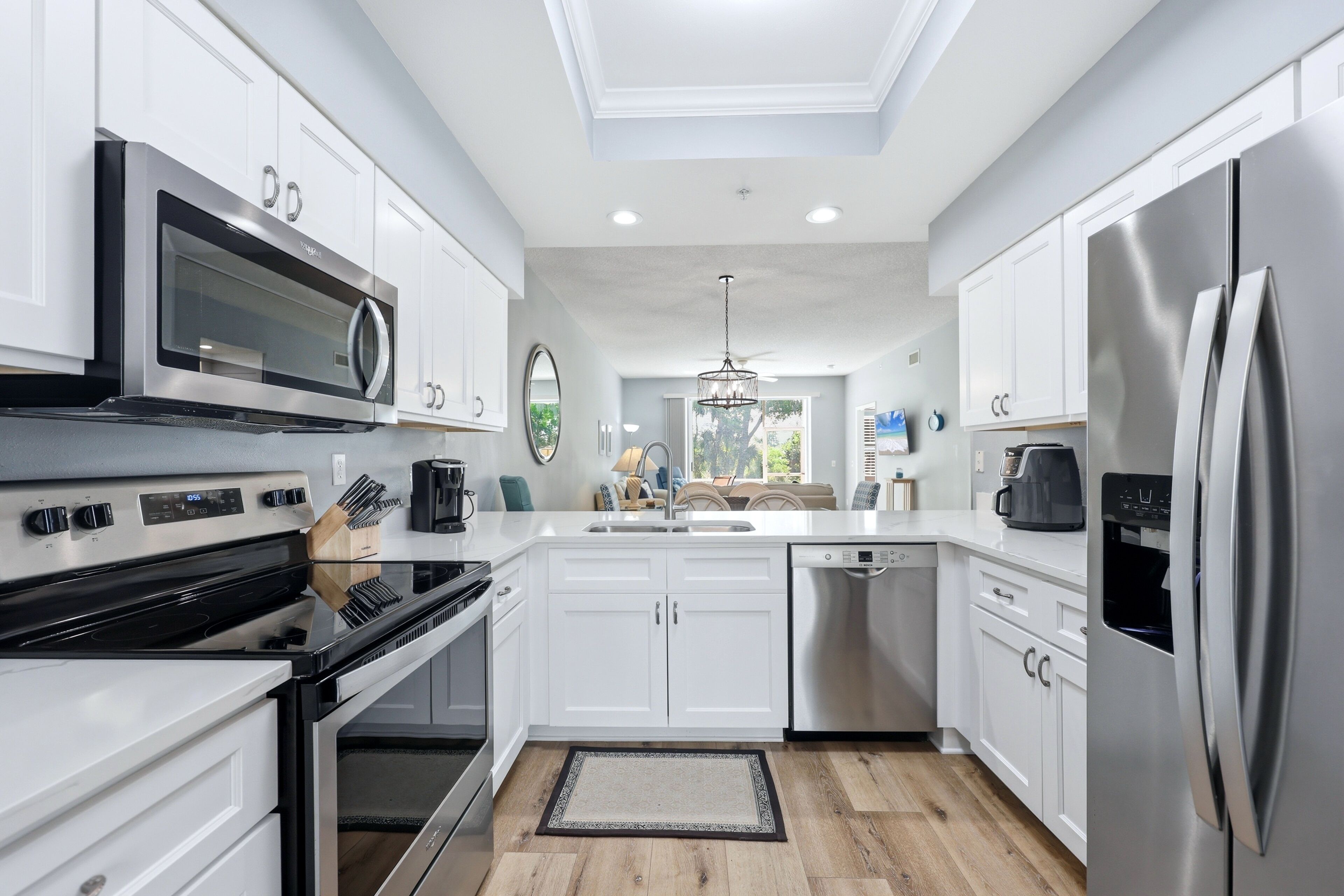 A modern kitchen with white cabinets, stainless steel appliances, and a central island.